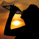 A woman drinks water during sunset in Cagnicourt, France, on June 25, 2019.